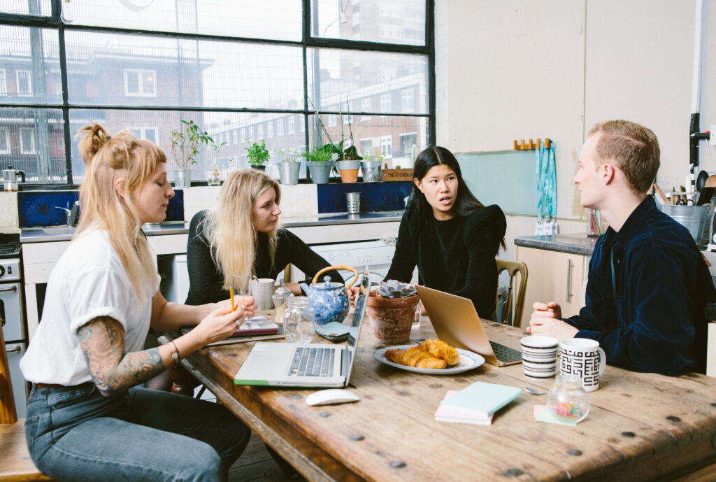 Un groupe de 4 personnes travaillent autour d'une table : 3 femmes et un homme